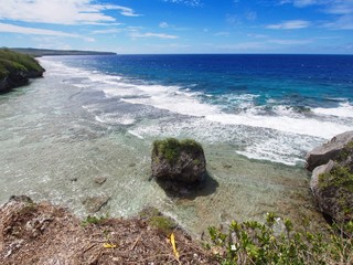 Panoramic coastal and ocean view from a cliff showing clear waters with a rock in a tropical island 