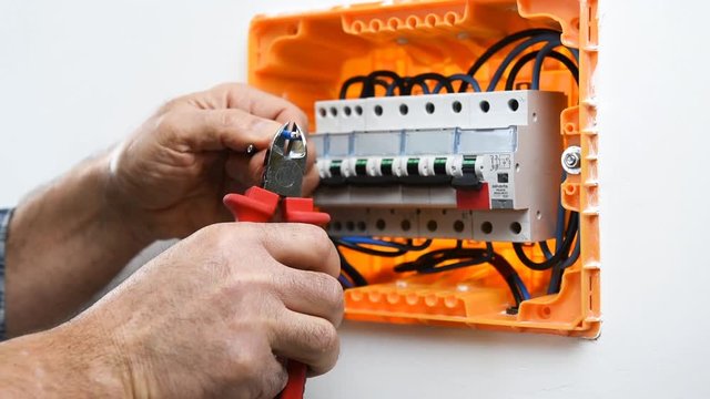 Video of the hands of the electrician technician cutting the electric cables in an electrical panel of a residential installation. Construction industry.