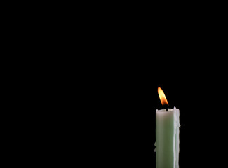 Burning pale green candle isolated on black background with place for text.