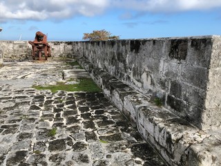 Wide shot inside the walls of Fort Charlotte with a canon in the background.