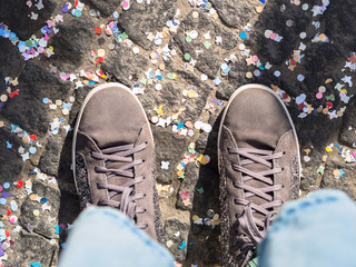 Pavement covered with colorful confetti and shoes