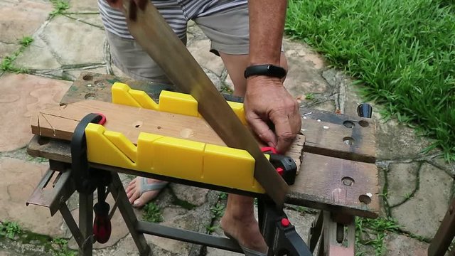 Corte com caixa de esquadria, fazendo corte com um serrote manual usando uma bancada
