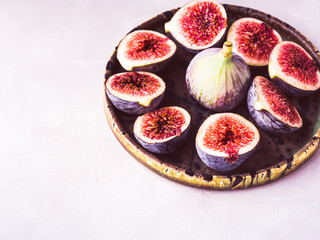 Dish of purple figs on stone background