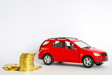 A stack of shiny yellow coins on a background of red car on a light gray background.