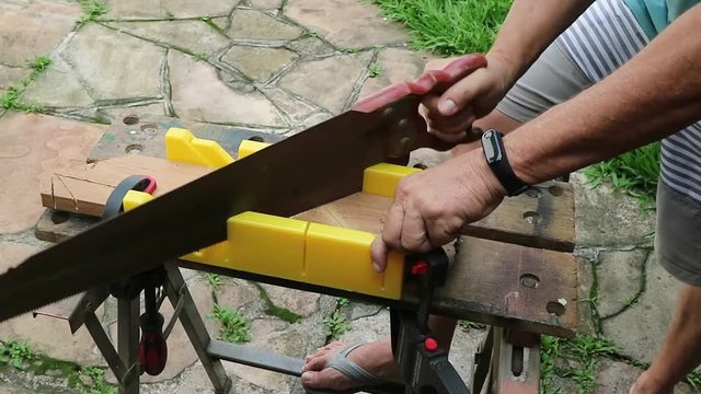 Corte com caixa de esquadria, fazendo corte com um serrote manual usando uma bancada