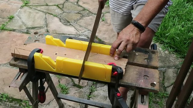Corte com caixa de esquadria,  fazendo corte com um serrote manual usando uma bancada