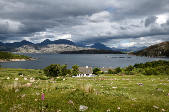 House at rocky Kenmore on Loch a Chracaich of Loch Torridon with sheep and fish farm pens Scottish Highlands Scotland UK © Reimar
