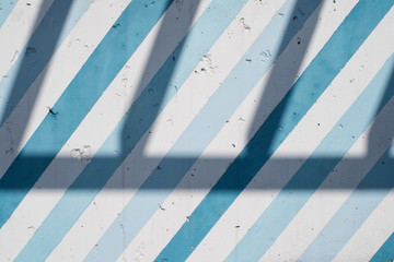 Painted concrete wall with diagonal blue and blue stripes and shadows