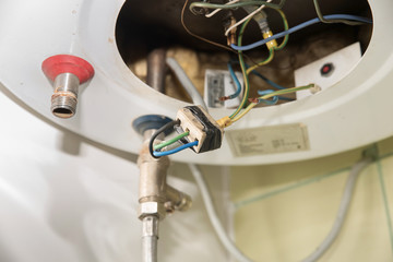 Inside of the broken water heater or boiler with electric wires and pipes for installation of the...