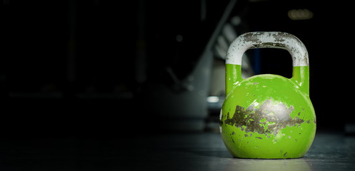 Naklejka na ściany i meble Heavy old used color kettlebell weight on the gym floor ready for fitness strength workout to build muscles with dark background and free copy space banner 