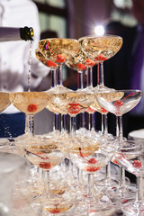 Champagne slide. Pyramid or fountain made of champagne glasses with cherry and steam from dry ice