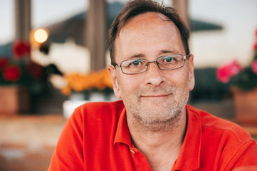 Outdoor portrait of 50 year old man wearing red polo shirt and eyeglasses - 252492406