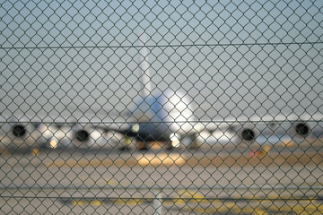 Sicherheitszaun und Flugzeug am Boden bei der Startvorbereitung - Stockfoto