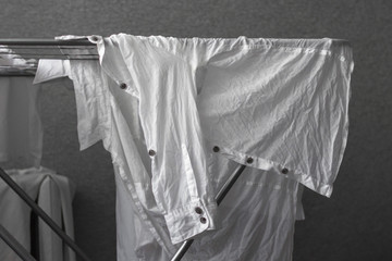Crumpled white shirt. Washed clothes on the dryer. Cotton shirt. Classic clothes in the wardrobe. Black and white background. Monochrome image. Shirt on a hanger. Piece of clothing.