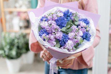 Bouquets of blue hyacinths and matthiola of lilac color in woman hand. Spring flowers from Dutch gardener. Concept of a florist in a flower shop. Wallpaper.