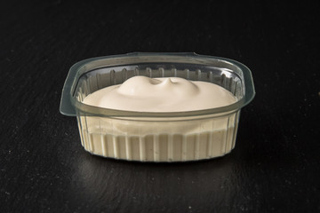 Sauce topping in plastic package for take away or food delivery isolated on a black background.