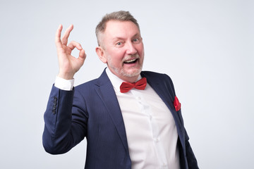 Senior man in elegant blue suit showing OK sign
