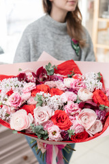 beautiful fresh cut bouquet of mixed flowers in woman hand. the work of the florist at a flower shop. Red and pink color