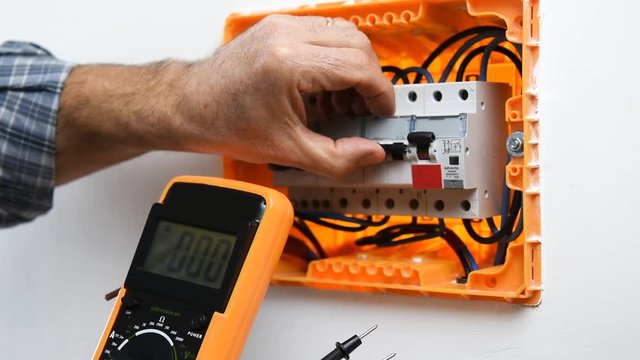 Video of the hands of the electrician technician who with the multimeter measures the voltage in an electrical switchboard of a residential installation. Construction industry.
