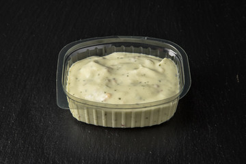 Sauce topping in plastic package for take away or food delivery isolated on a black background.
