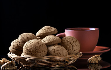 Oatmeal cookies and a cup of coffee on a black table.