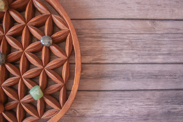 A wooden flower of life sacred symbol with chakra stones on a wooden background.