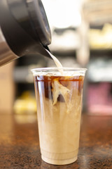 pouring milk into iced coffee
