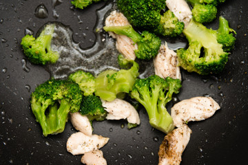 Broccoli fry in a pan with slices of meat. Chicken meat with broccoli.