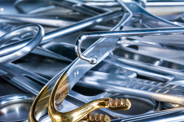 set of instruments with one hook in the middle, the backside of a scissor, golden pieces in the...