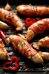 Spicy chicken meat, Grilled chicken tenderloin wrapped with bacon with addition chili peppers, garlic and herbs on grill plate, close-up top view