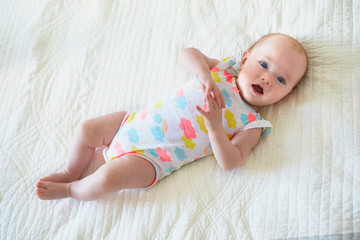 Baby girl lying on bed and smiling