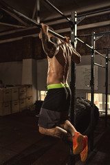 Athletic man performing pull ups at the gym