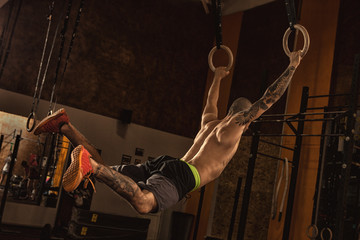Male athlete working out on gymnastics rings at the crossfit gym
