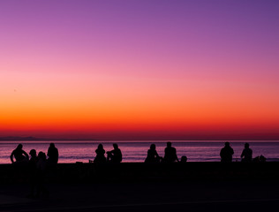 Fototapeta na wymiar SAN SEBASTIAN, SPAIN - March 02, 2019: People in backlight at the sea at sunset, city of San Sebastian