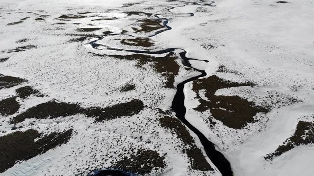 survol d'une rivi&egrave;re qui serpente sur un plateau neigeux