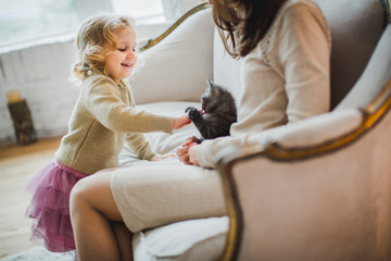 Mother and daughter are playing with kitten