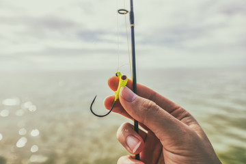 Fishing hook closeup watersport gear. Woman hand holding line.