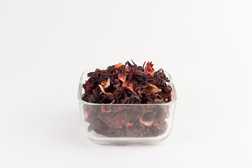 petals of dry hibiscus tea  in the transparent bowl isolated on white background