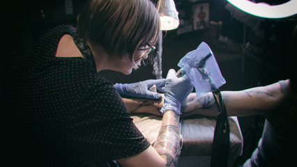 Tattoo artist make tattoo in studio, tattooing on the body. Floral tattoo