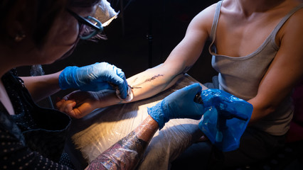 Tattoo artist make tattoo in studio, tattooing on the body. Floral tattoo