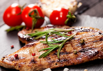 Grilled beef steak with vegetables and spices on black background