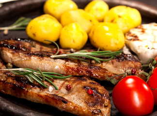 Grilled beef steak with vegetables and spices on black background