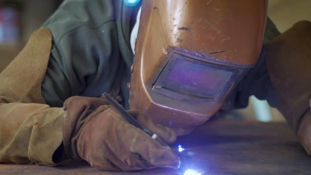Metal work puts down his welding helmet and starts joining two pieces of copper