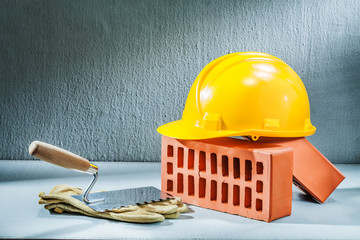 bricks helmet gloves and trowel on concrette