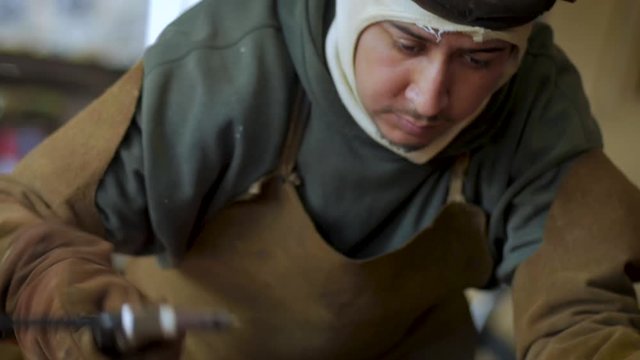 Metal worker hammering and welding copper in slow motion