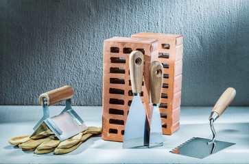 set of plastering trowels gloves and bricks on concrette background