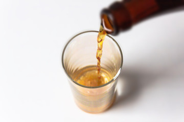 Pouring beer from bottle, isolated on white background.