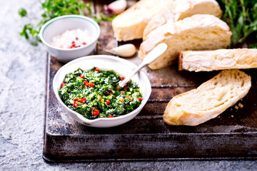  Argentinian green Chimichurri with ingredients.Raw homemade with ciabatta.Salsa or sauce made of parsley, garlic, oregano, hot pepper, olive oil, vinegar.Food Concept.