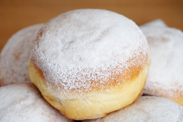 Sweet dessert with powder white sugar. Plate with tasty doughnuts with one on the top