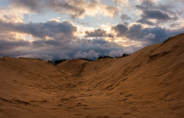 Fototapeta na wymiar volumetric clouds on a background of sandy desert at sunset